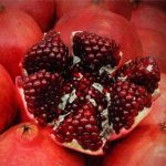 there are a lot of pomegranates and one of them is cut into slices