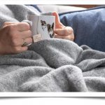 Женщина с кружкой напитка укрылась байковым одеялом